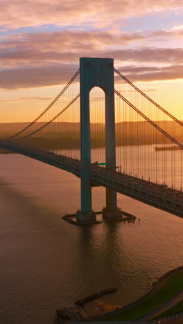whitestone bridge over east river at setting sun. sun reflecting in the calm water. non-stopping traffic of new york. vertical video