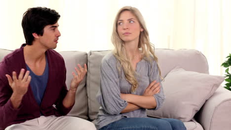 una pareja discutiendo en el sofá.