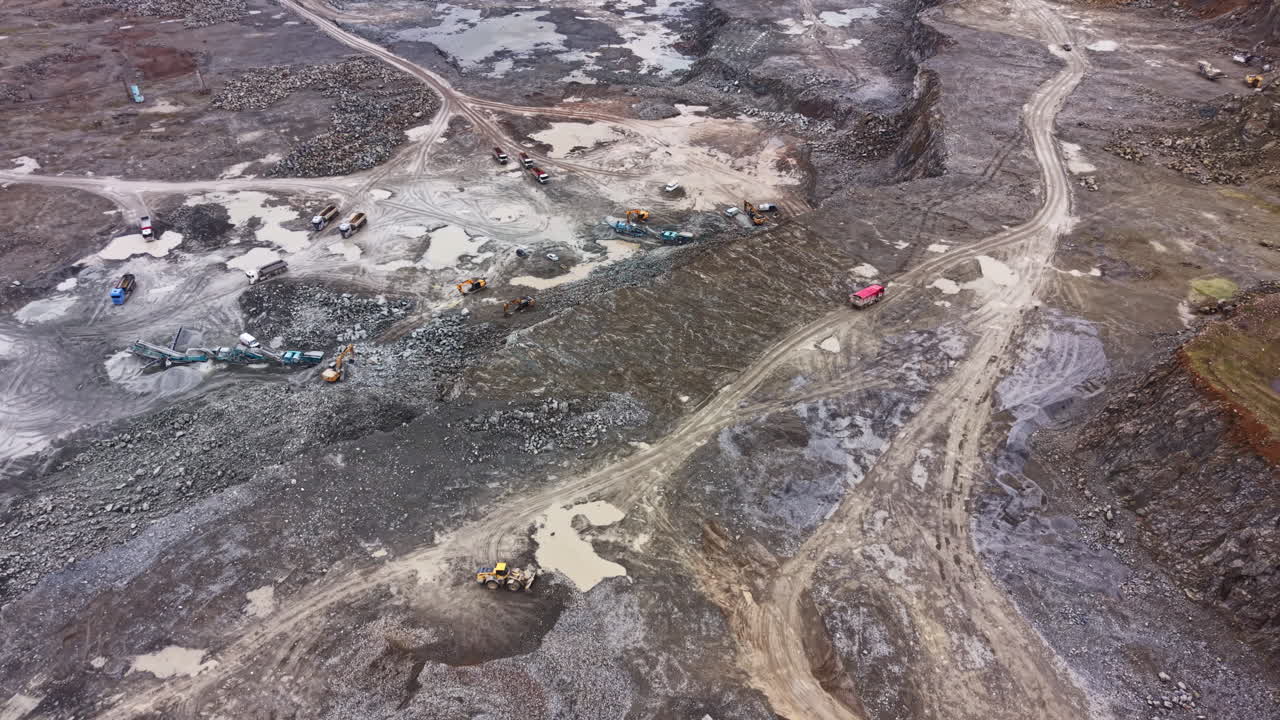 Granite quarry operation in large site with heavy machinery and various activities during daylight hours