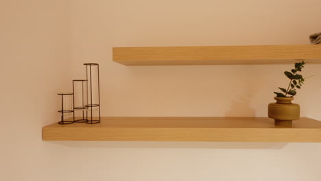 paneo a la derecha que revela un estante de pared de madera con pocos objetos