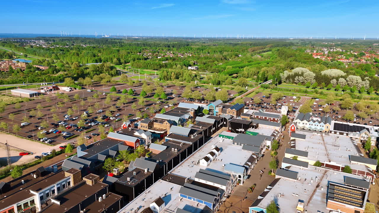 Flying above the terraced houses and streets. Approaching the parking lots at the backdrop of lush greenery. Aerial view. Lelystad, the Netherlands.