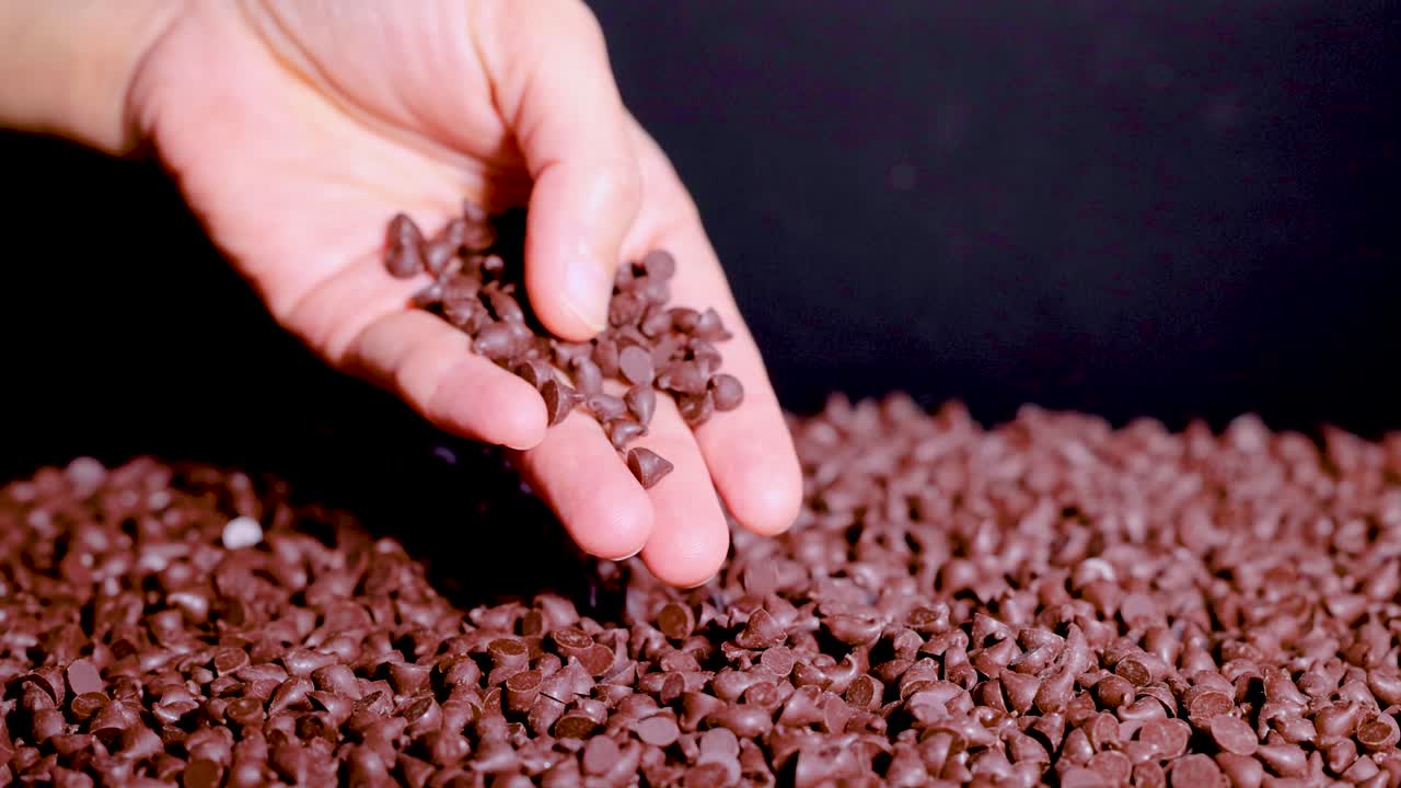 Hand scooping chocolate chips from a pile