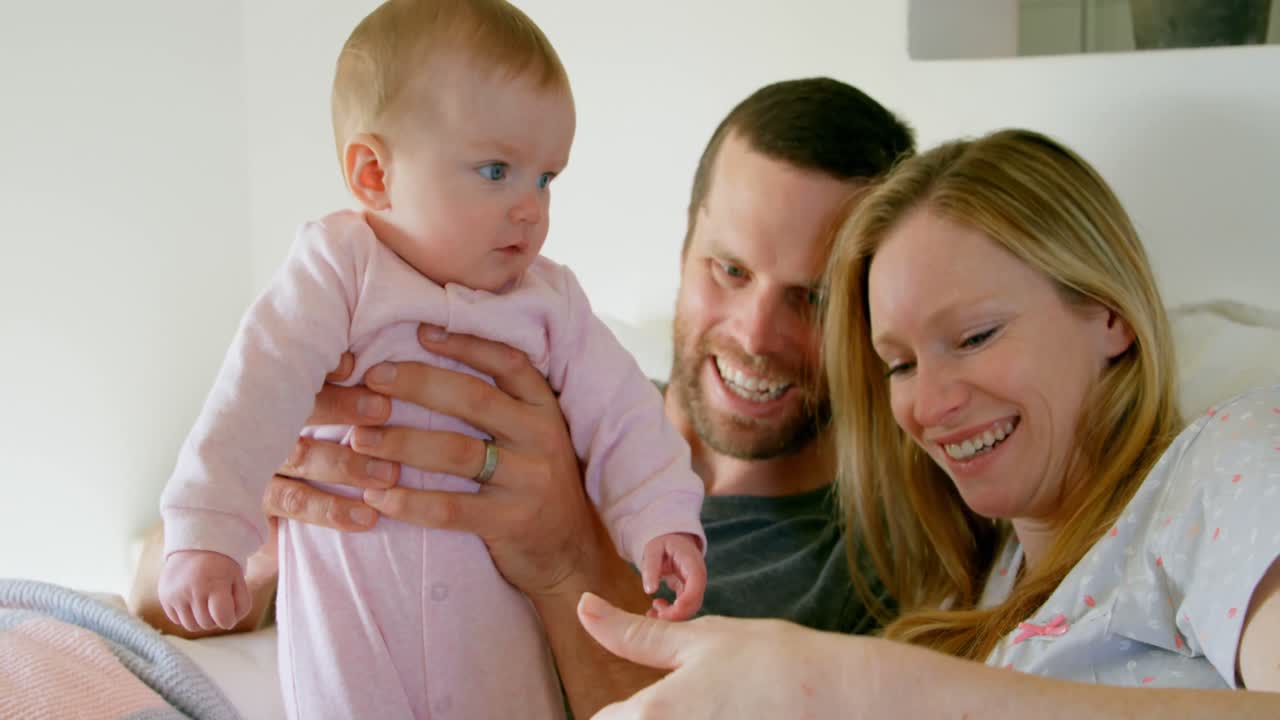 백인 부모가 집의 침실에서 아기와 함께 재미를 느끼는 전면 뷰 4k