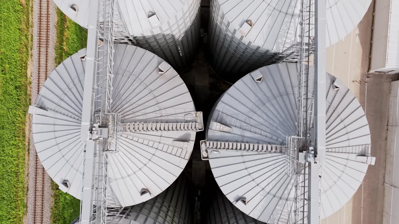 Smooth backward aerial shot of silver grain silos in Latvia under cloudy sky