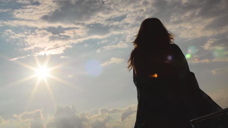 a woman in a long flowing dress dances by herself in the sunshine. her figure is silhouetted with beauty. she celebrates life and happiness in her femininity