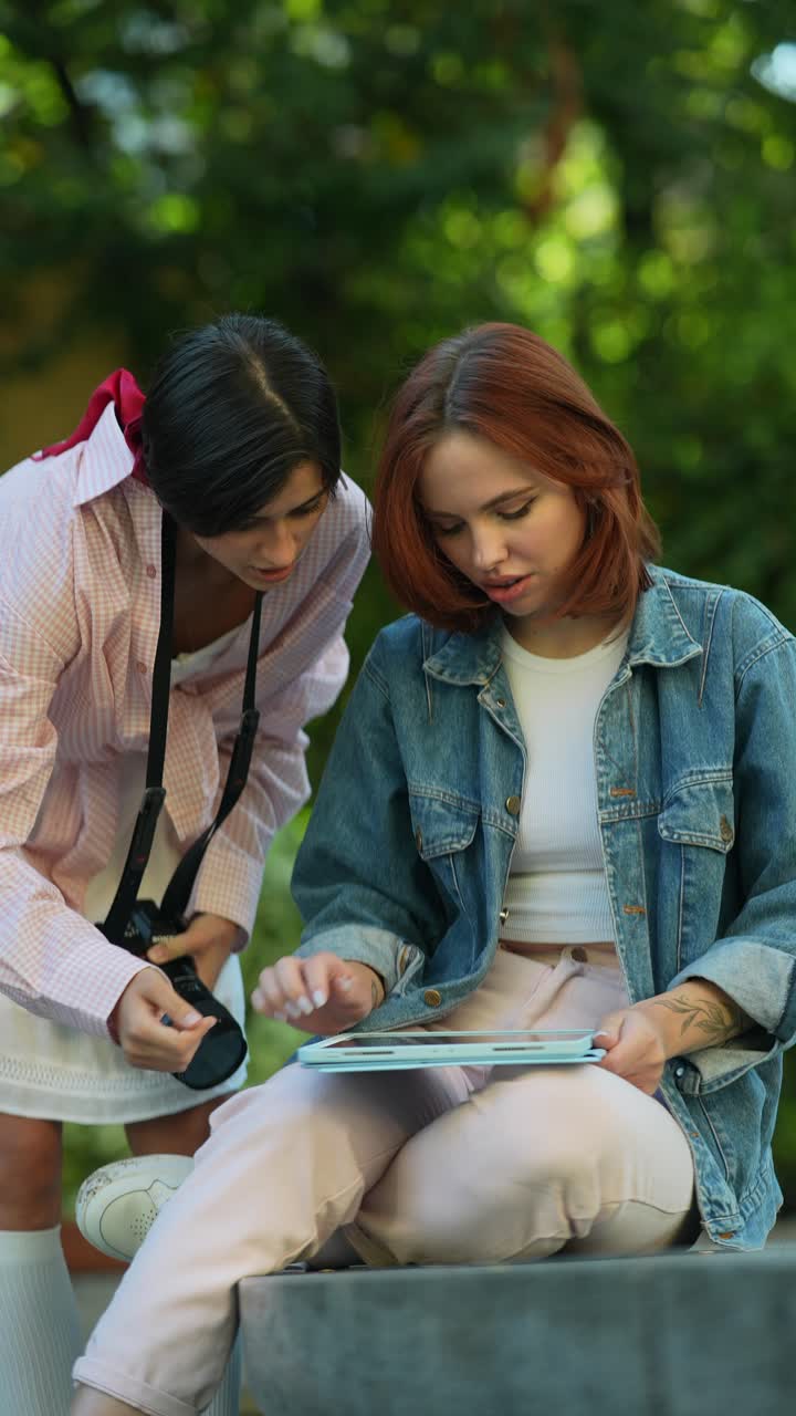 dos mujeres colaborando en una tableta afuera
