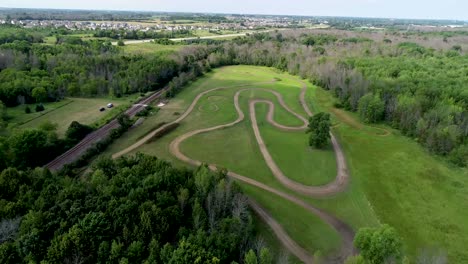 aerial flyover of motorcycle dirt track hidden in woods along large lake