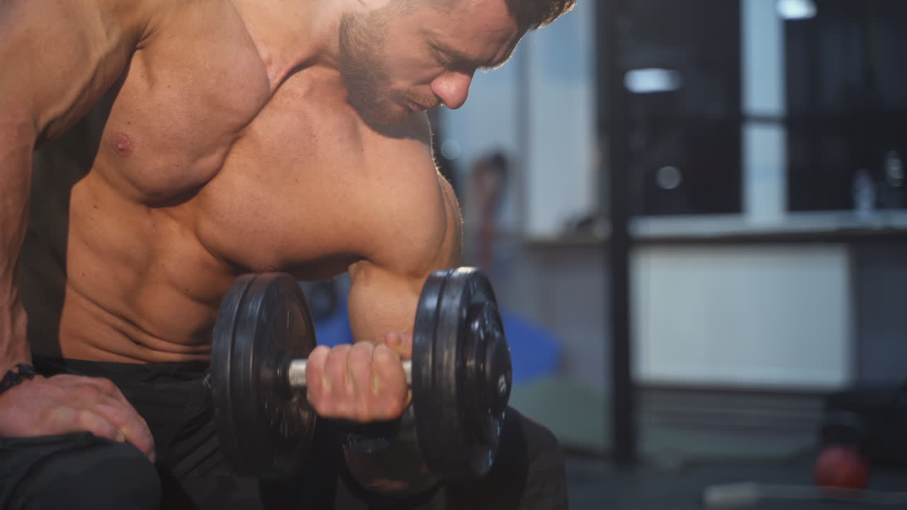 Young muscular man training hard at the gym. Bodybuilding man training his biceps.