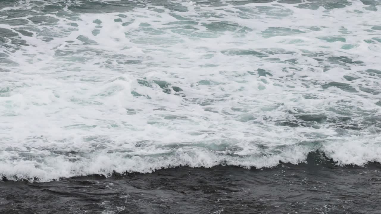 역동적인 바다 파도가 거대한 바다 도로를 따라 바위가 있는 해변에 부히는 모습, 자연 조명에서 고정된 카메라로 촬영