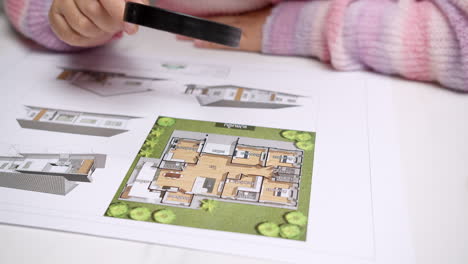 an individual looking at the architectural plan and checking thoroughly with a magnifying glass