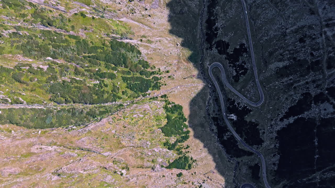 Transfagarasan road winding through mountains, aerial view, dramatic shadows