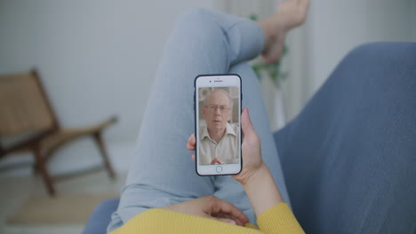 vista por encima del hombro de una mujer joven hija video llamando a padres viejos padre o amigo maduro usando la aplicación de chat de conferencia en línea en la pantalla del teléfono móvil en la oficina de casa. concepto de videoconferencia familiar