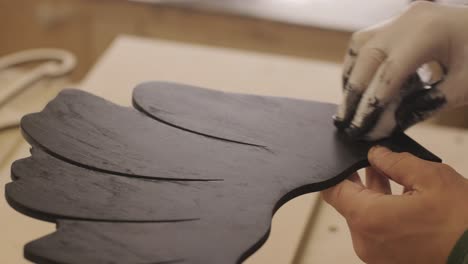 A worker hands paints a wooden product with a sponge. Painting of plywood products made on a cnc laser machine