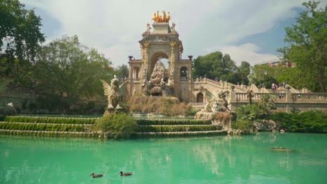 Impresionante-Video-De-Una-Chica-Con-Vestido-Verde-Y-Gorro-De-Punto-Viendo-La-Cascada-Monumental-En-El-Parque-De-La-Ciutadella,-Barcelona---España