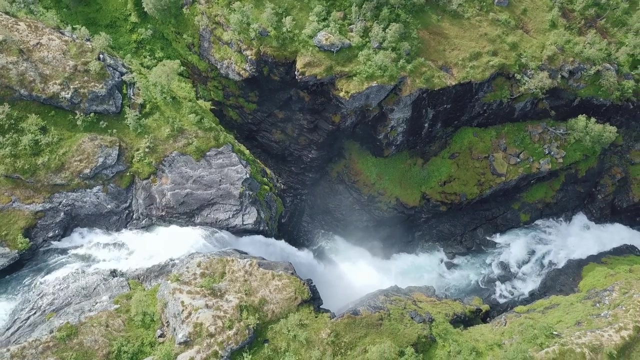 Ilmakuva kallistuu vasemmalle, näkymä voimakkaasta vesiputouksesta. Lähellä Norjan Trollstigeniä.