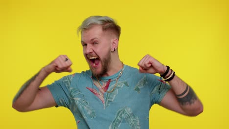 Stylish-man-in-t-shirt-shouting,-raising-fists-in-gesture-I-did-it,-celebrating-success,-winning