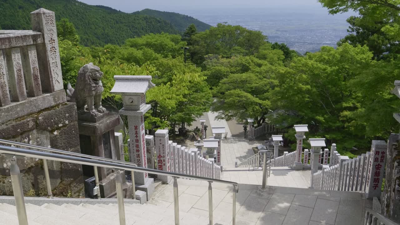 Slow cinematic tilt up reveal over stone steps at Japanese temple with panorama view