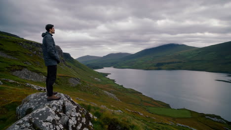 A man stands in a dramatic landscape, overlooking a lake and mountains, with close-up views of his reflective gaze