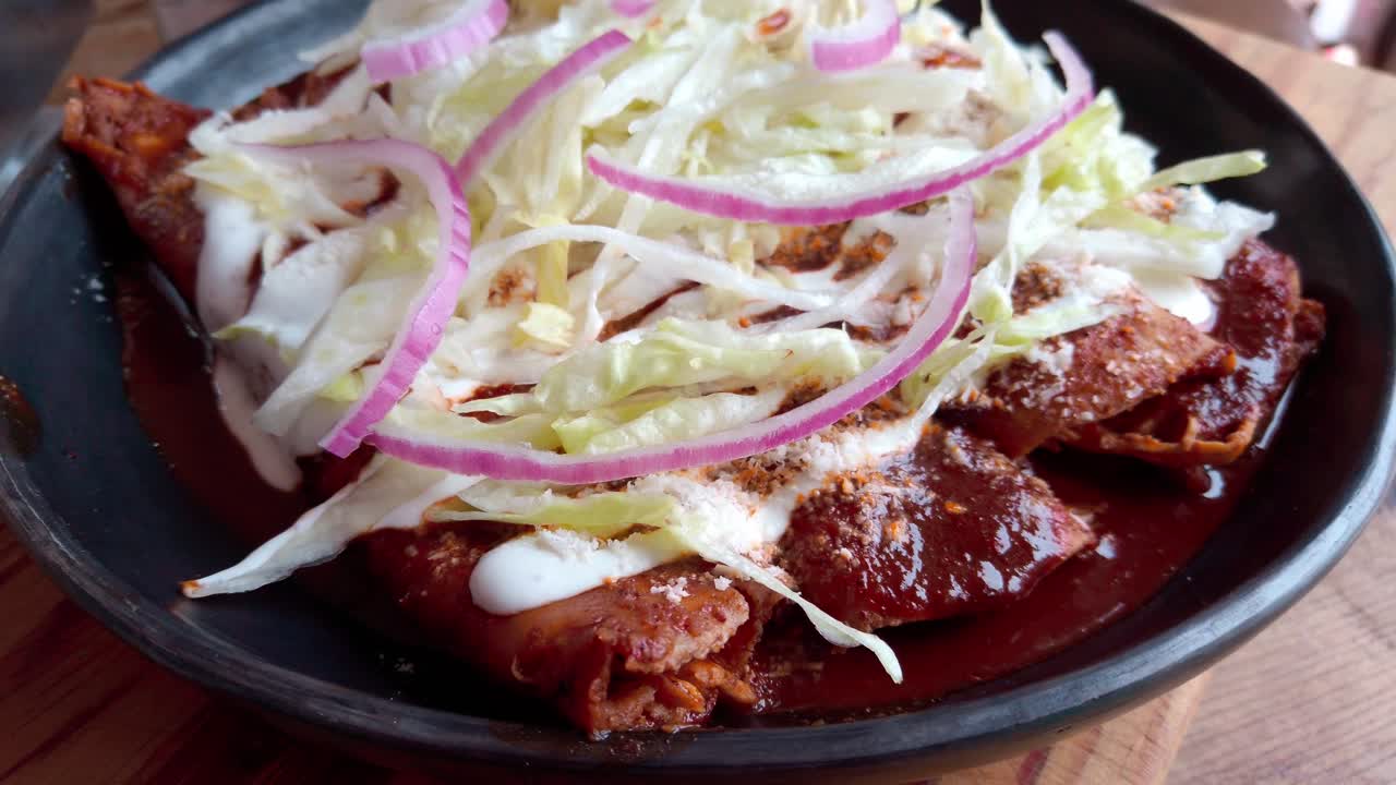 Fresh enchiladas topped with shredded lettuce, red onions, and a creamy sauce