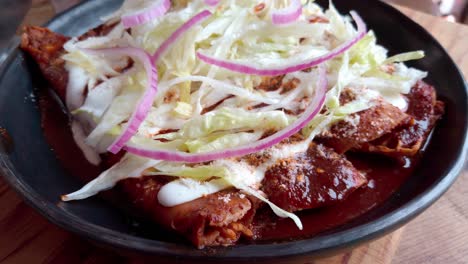 fresh enchiladas topped with shredded lettuce, red onions, and a creamy sauce