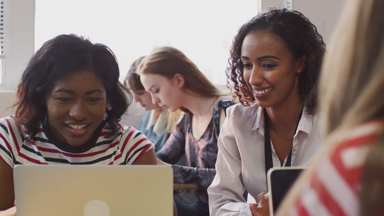 maestra dando apoyo uno a uno a una estudiante que trabaja en un escritorio en una computadora portátil