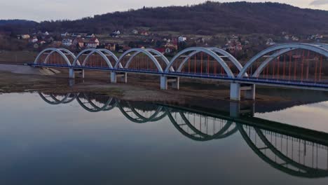 railway arch bridge with specular reflection on the river with town houses in the background