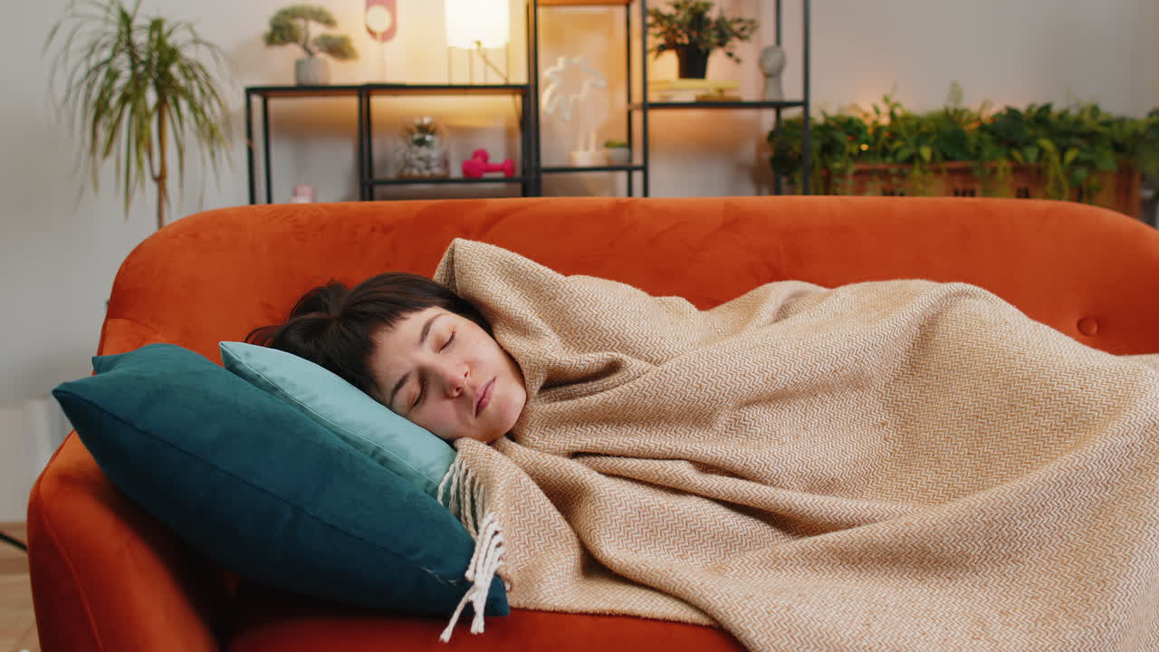 Tired caucasian woman sleeping quietly covers with blanket on sofa resting peacefully healthy sleep