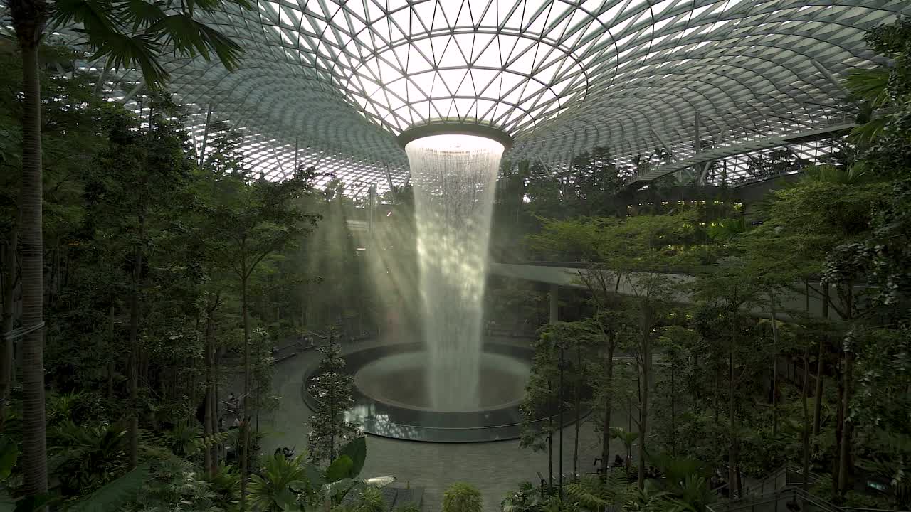 Light leaks through the indoor forest and world's tallest indoor waterfall in Jewel Changi Airport in Singapore slowmo