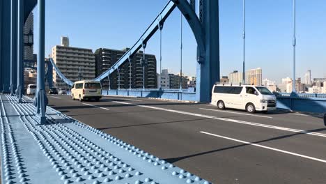 various vehicles travel across a bridge in daylight.