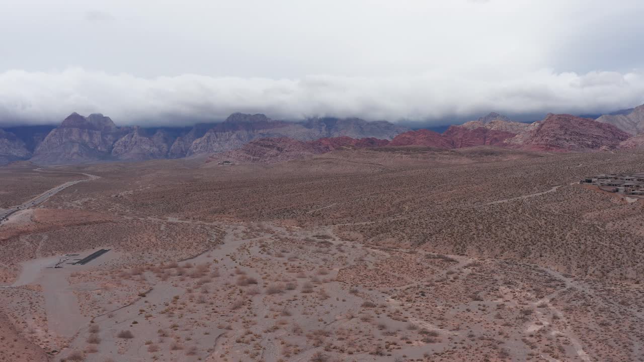 amplia toma aérea descendente del cañón de roca roja con espesas nubes sobre las montañas en las vegas, nevada