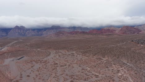 wide descending aerial shot of red rock canyon with thick clouds over the mountains in las vegas, nevada