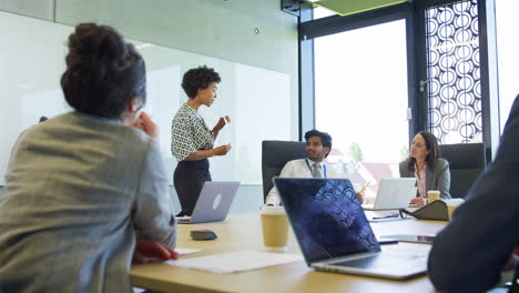 Multi-Cultural-Business-Team-Applauding-Businesswoman-Leading-Meeting-Around-Table-In-Modern-Office