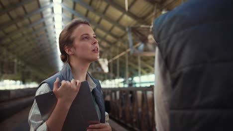 farm manager talking cowshed with colleague. livestock workers inspect feedlots.