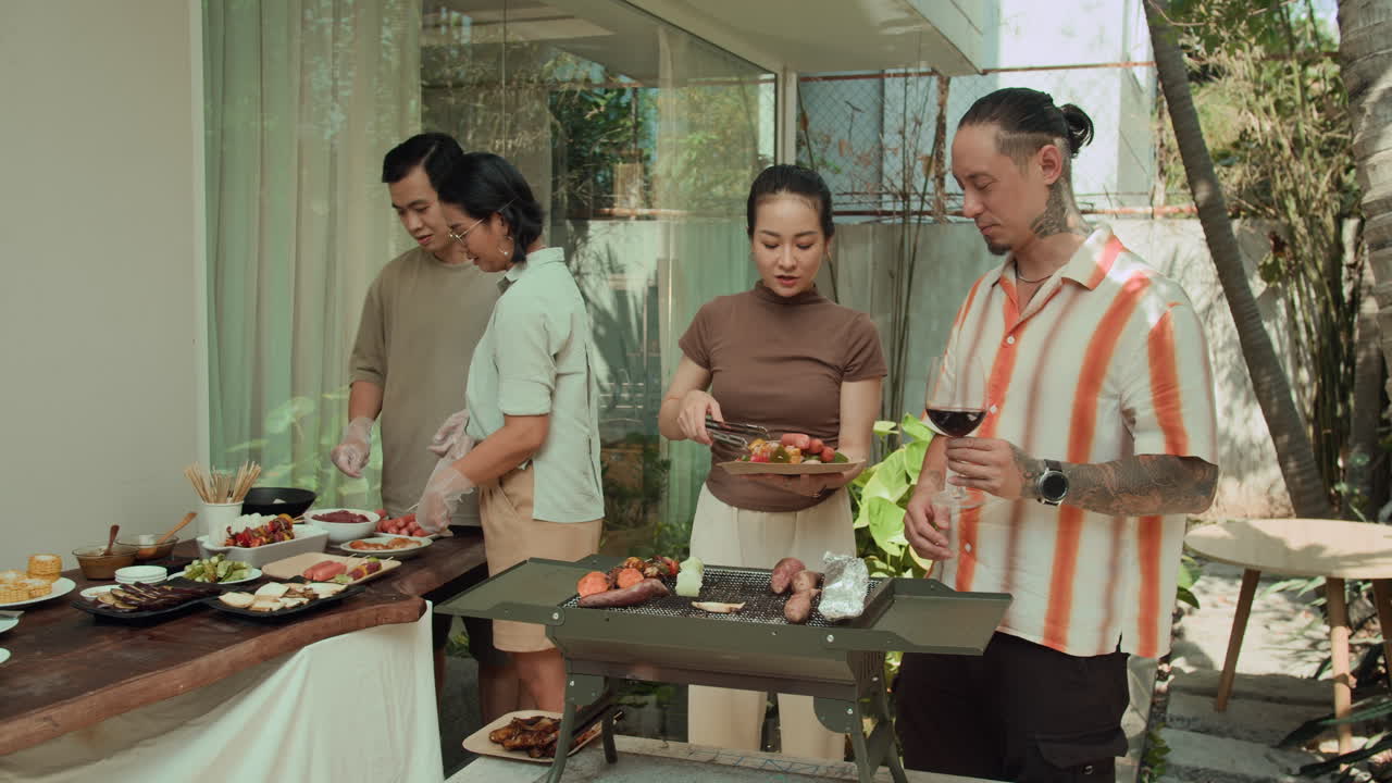 Company of Friends Chatting when Barbecuing in Backyard