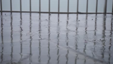 Raindrops-ripple-on-street,-static-handheld