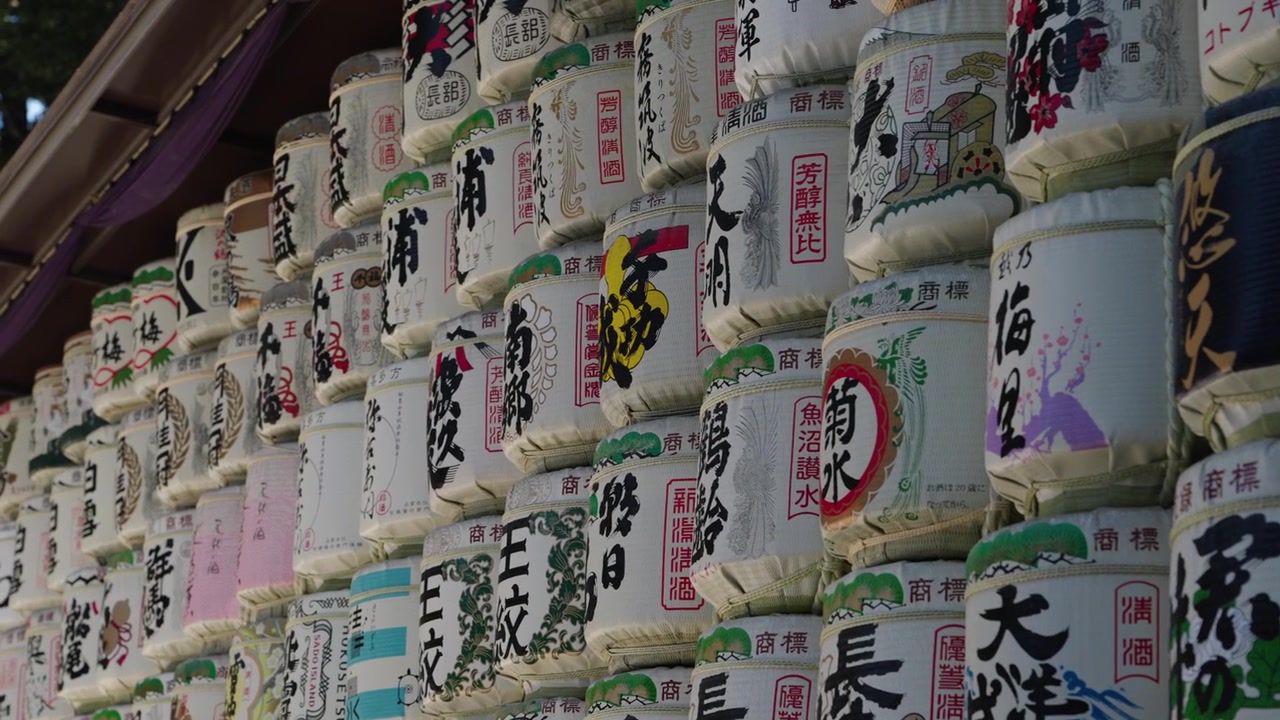 Primo piano di botti di sake votive impilate con dettagliata calligrafia kanji ed etichette dipinte colorate, Santuario Meiji Tokyo.