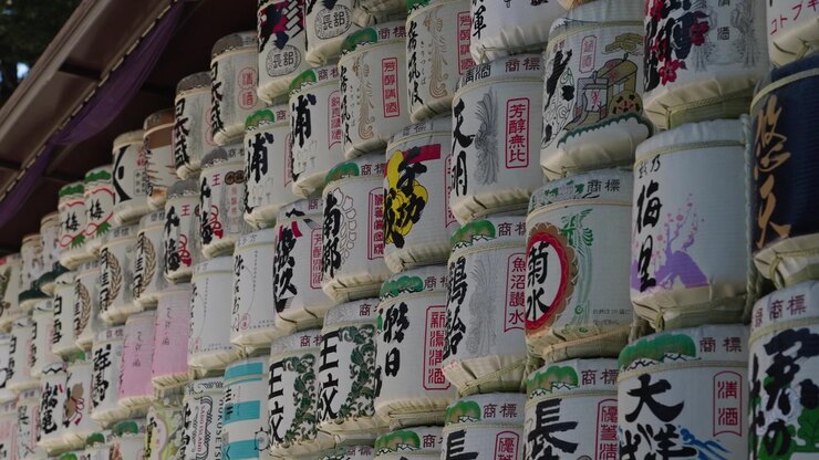 Primo piano di botti di sake votive impilate con dettagliata calligrafia kanji ed etichette dipinte colorate, Santuario Meiji Tokyo.