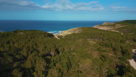 Tropical-beach-bay-with-green-hills,-clear-turquoise-sea-water,-white-sand