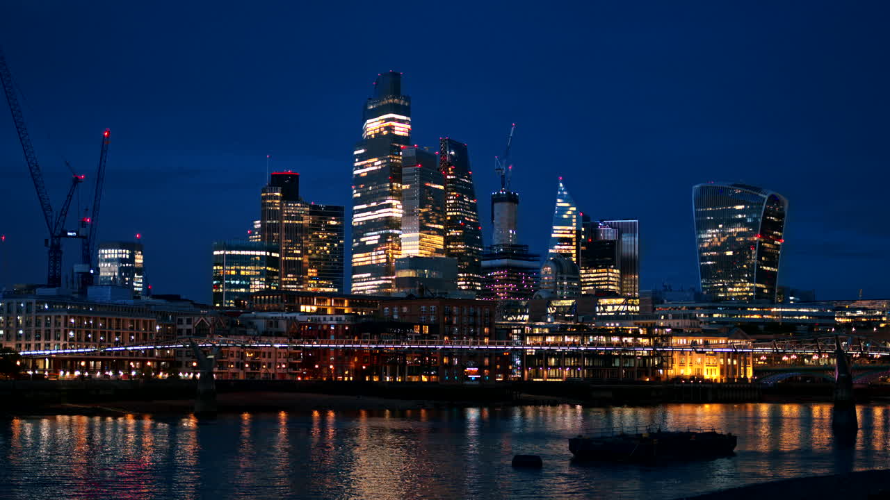 Cityscape of London downtown at evening, United Kingdom. Skyscrapers in City district, Thames River with the Millennium Bridge over it, a lot of illumination