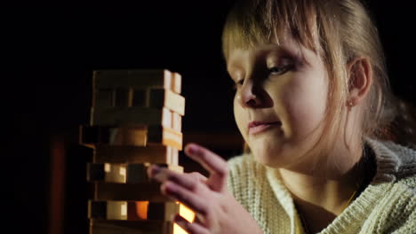 Portrait-Of-A-Child-Playing-A-Game-Where-You-Need-To-Take-Out-Wooden-Blocks-From-The-Tower