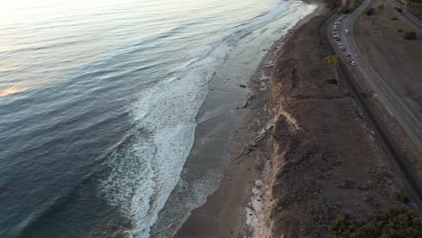 Langsames-Schwenken-Einer-Drohne-Als-Aufnahme-Von-Meereswellen,-Die-Während-Der-Goldenen-Stunde-An-Einen-Strand-Vor-Der-Küste-Kaliforniens-In-Der-Nähe-Des-Highway-101-Krachen