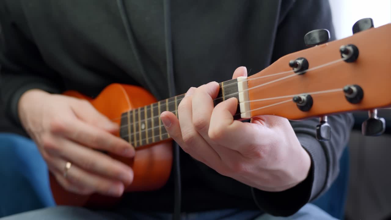 Married man playing ukulele, close up view