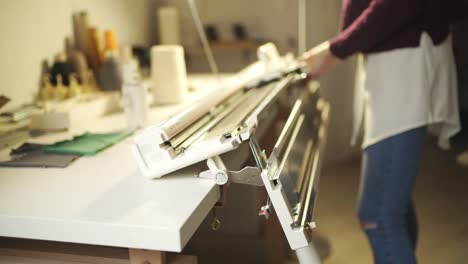 young woman adjust knitting machine for working in home workshop