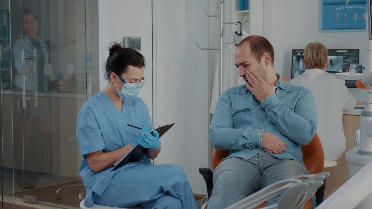 Dentistry nurse taking notes and talking to patient about toothache