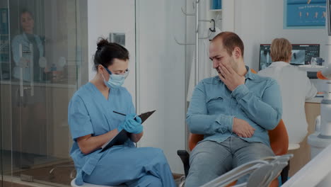 dentistry nurse taking notes and talking to patient about toothache