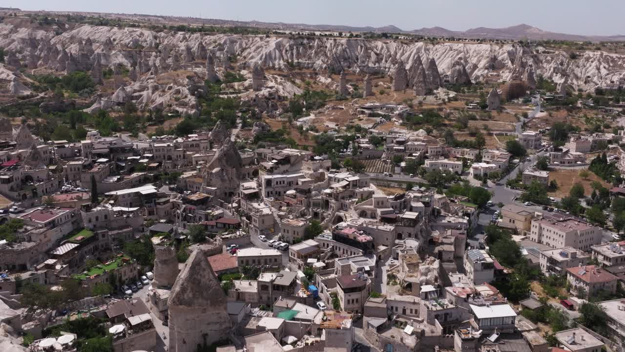 Panoramic aerial establishing overview of homes growing out of rock towers in Cappadocia Turkey at midday