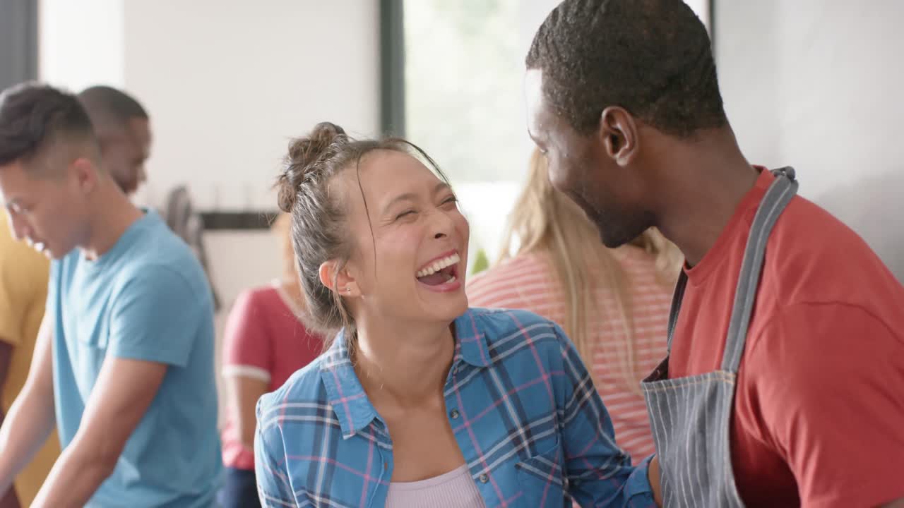 un grupo feliz y diverso de amigos preparando la comida en la cocina, cámara lenta
