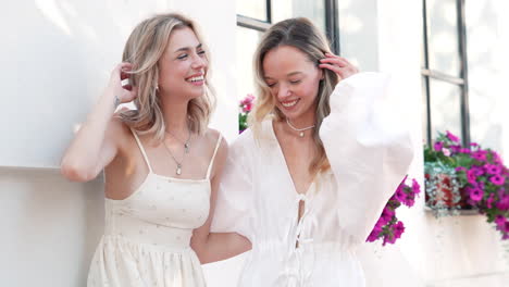 two women laughing outdoors in summer clothes