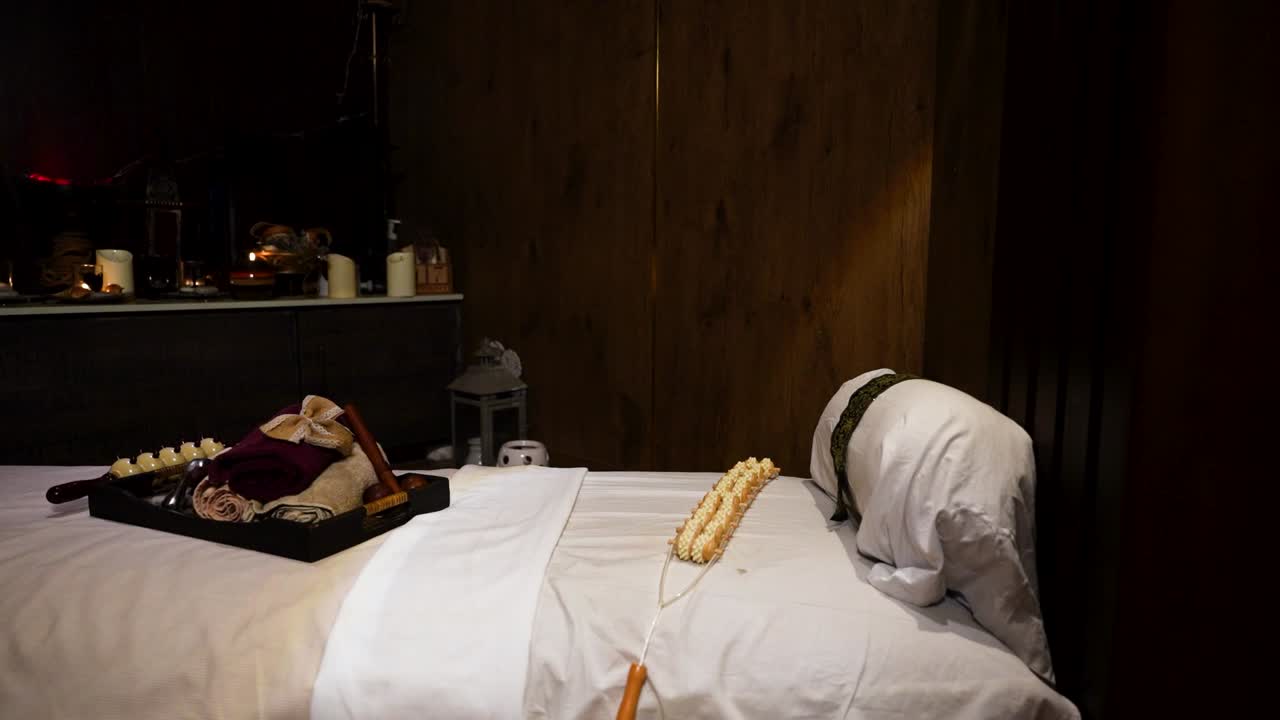 Interno di una sala massaggi con elementi essenziali per spa, candele e un lettino per trattamenti decorato, pronto per l'uso