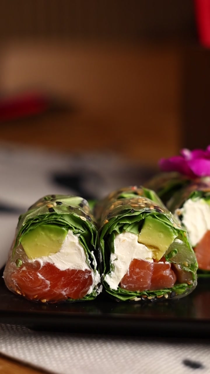 Involtini primavera freschi con salmone e avocado su un piatto nero